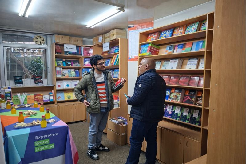 “Two ELT teachers having a discussion during the coffee break at the January 2026 Teachers’ Space session, surrounded by educational book displays at Nouresham Book Centre.”